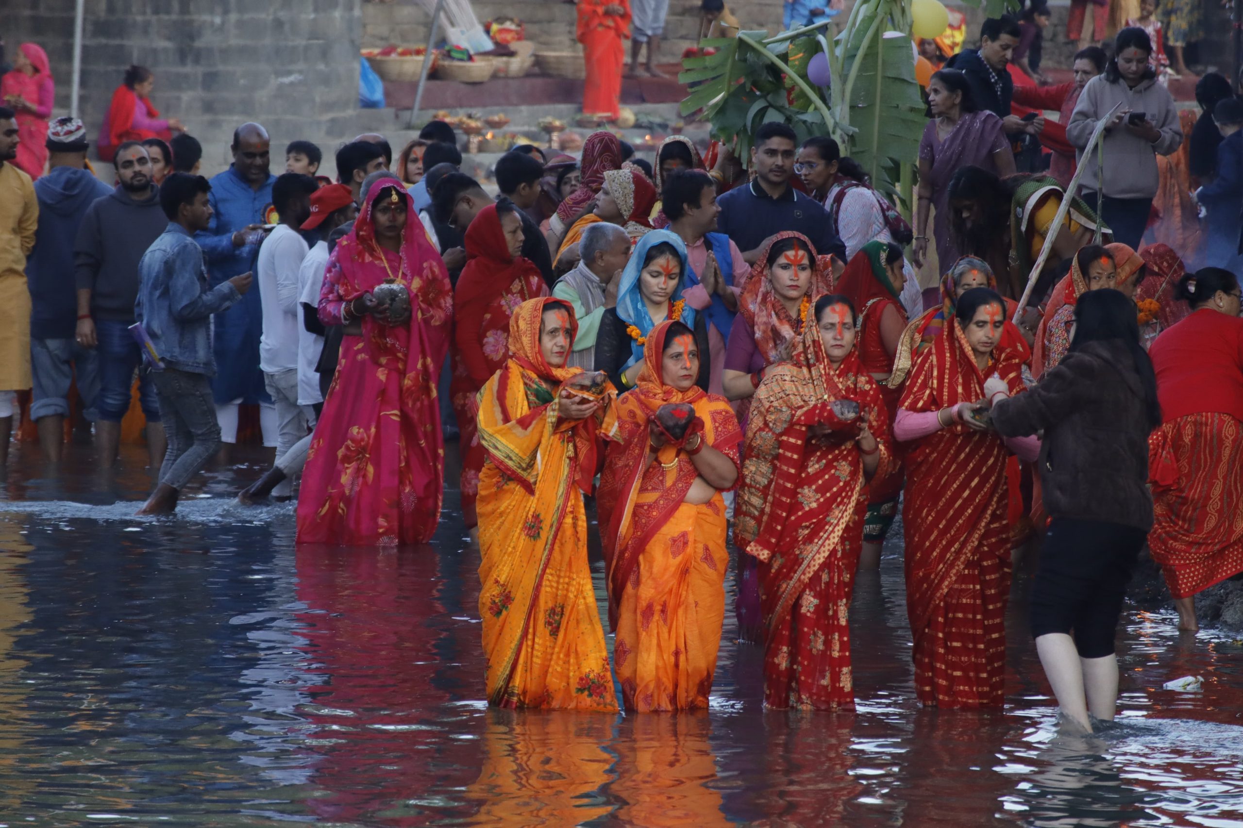 तस्बिरमा अस्ताउँदो सूर्यलाई अघ्र्य दिँदै व्रतालुहरू